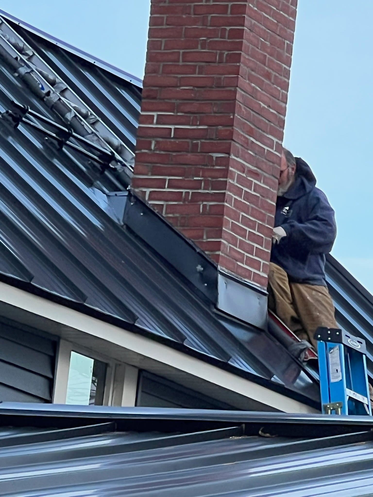 A standing seam roof expertly fitted around a chimney