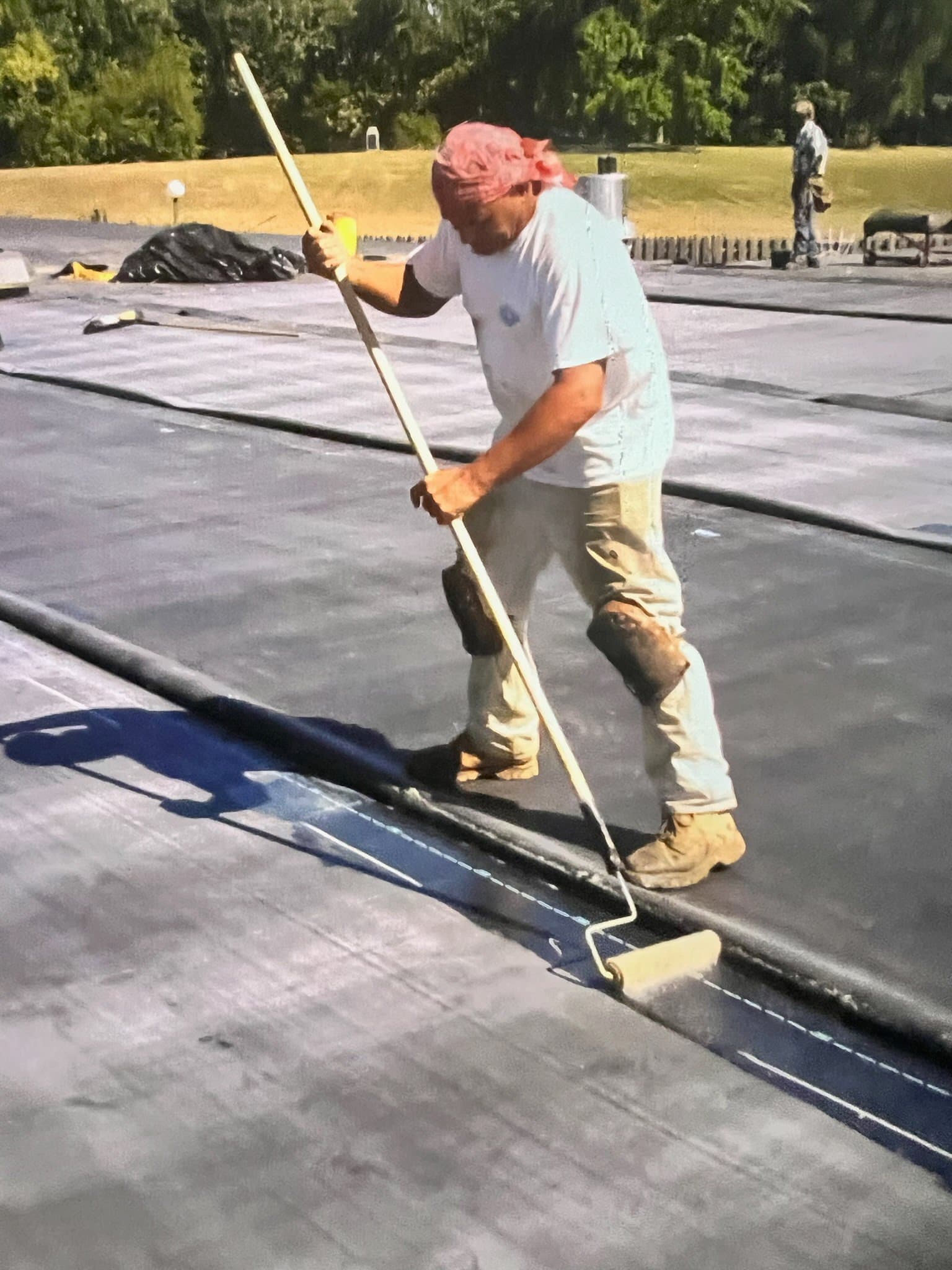 A worker rolling flat roofing material