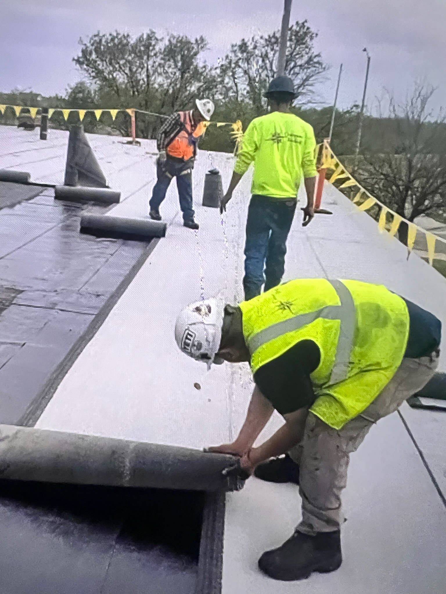 Roofing workers rolling out roofing material